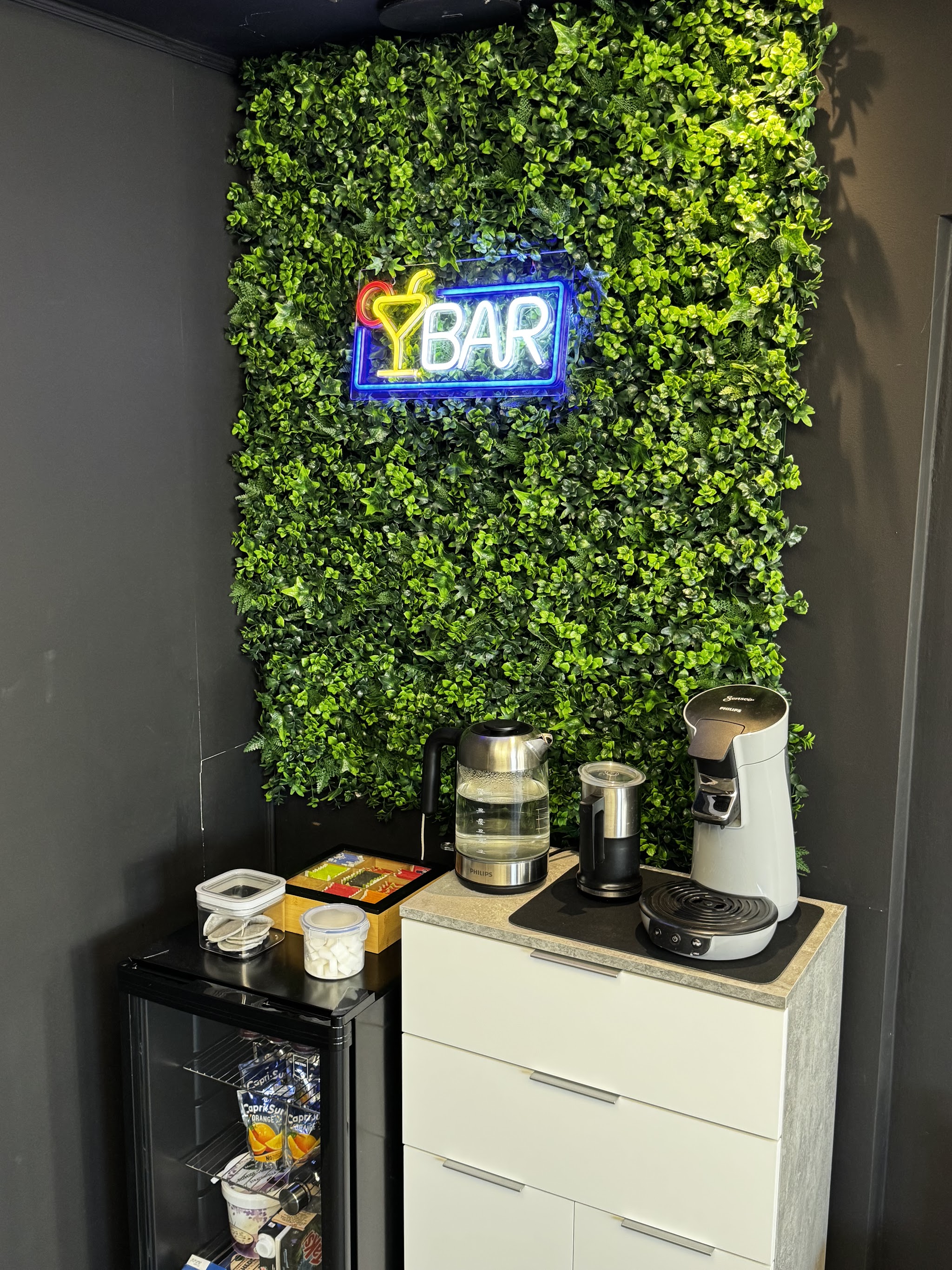 Koffiehoek met een groene wand en verlicht bord